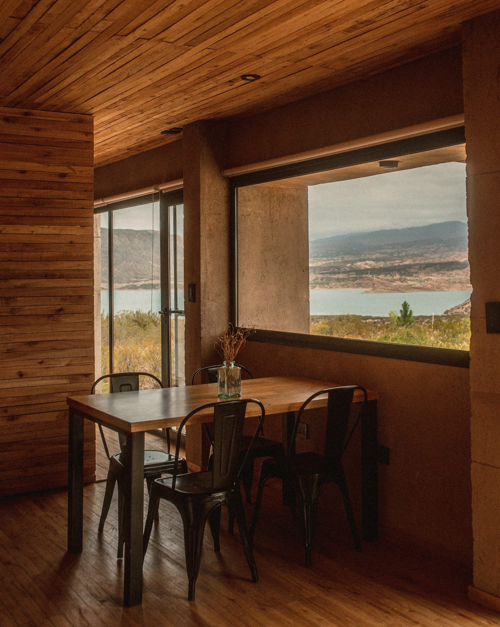 Comedor de Cabaña 'La Calma Ecolodge', iluminado naturalmente con vista el Dique de Potrerillos, en Mendoza, Argentina.