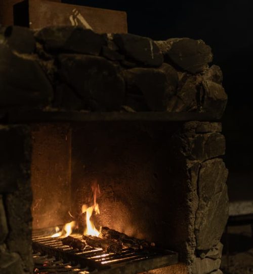 Fuego de leña en parrilla al aire libre dentro del complejo La Calma Ecolodge, en Mendoza.