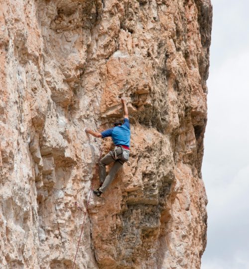 Scaling a rugged rock wall during daylight, showcasing extreme climbing skills. La Calma Ecolodge.
